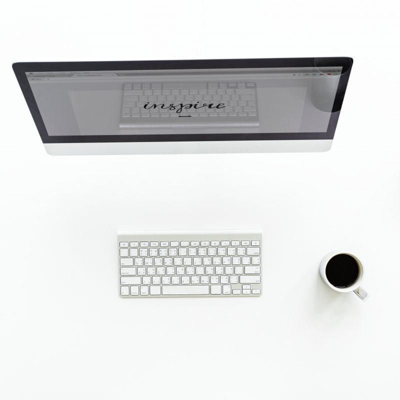 Very clean work station with a keyboard, monitor, black coffee and a succulent plant.
