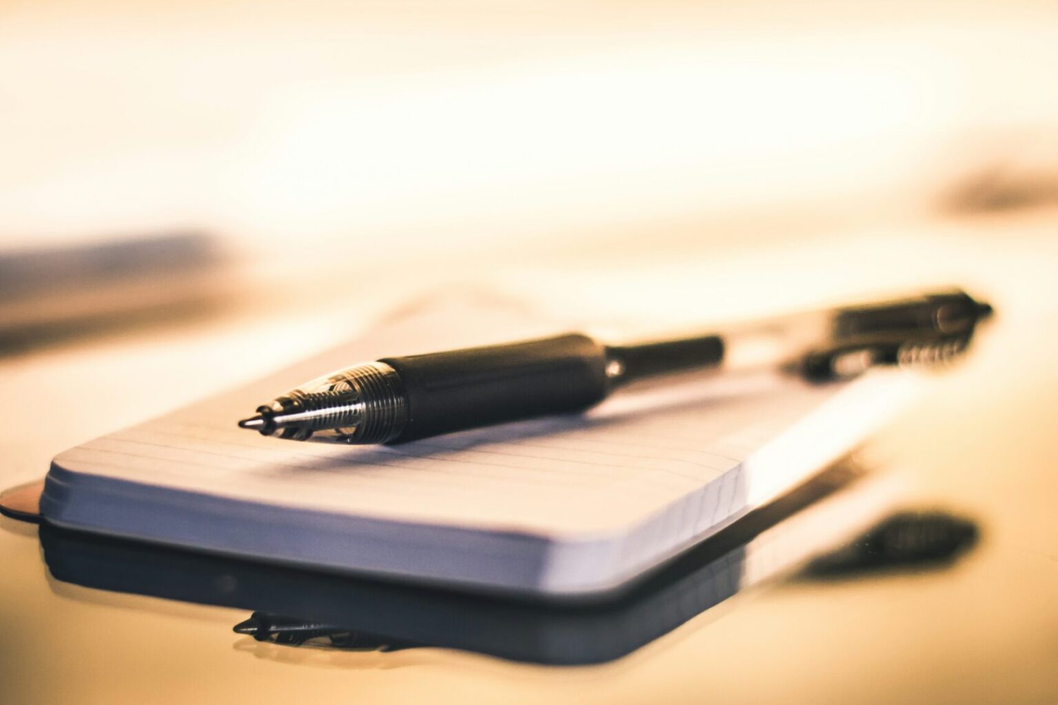 an image of a pen resting on a small pad of paper, ready to write a list of goals