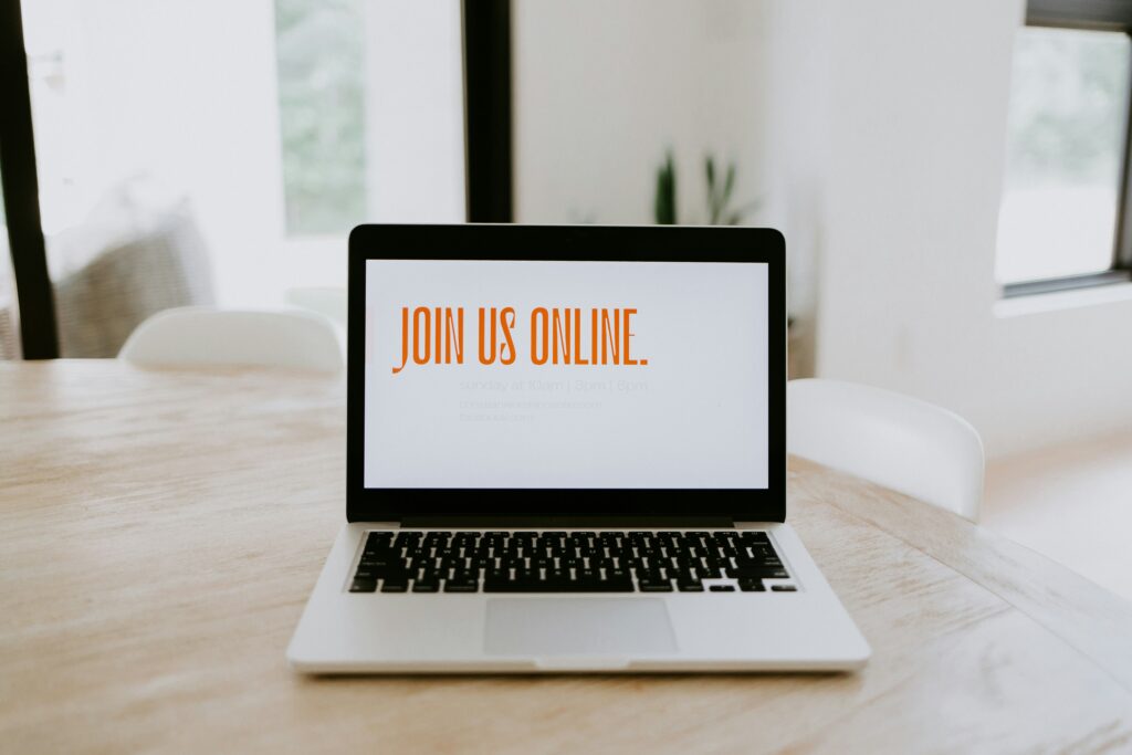 View of a laptop in a table top, with the words Join Us Online written on the laptop screen to hint at selling in your sleep via online courses